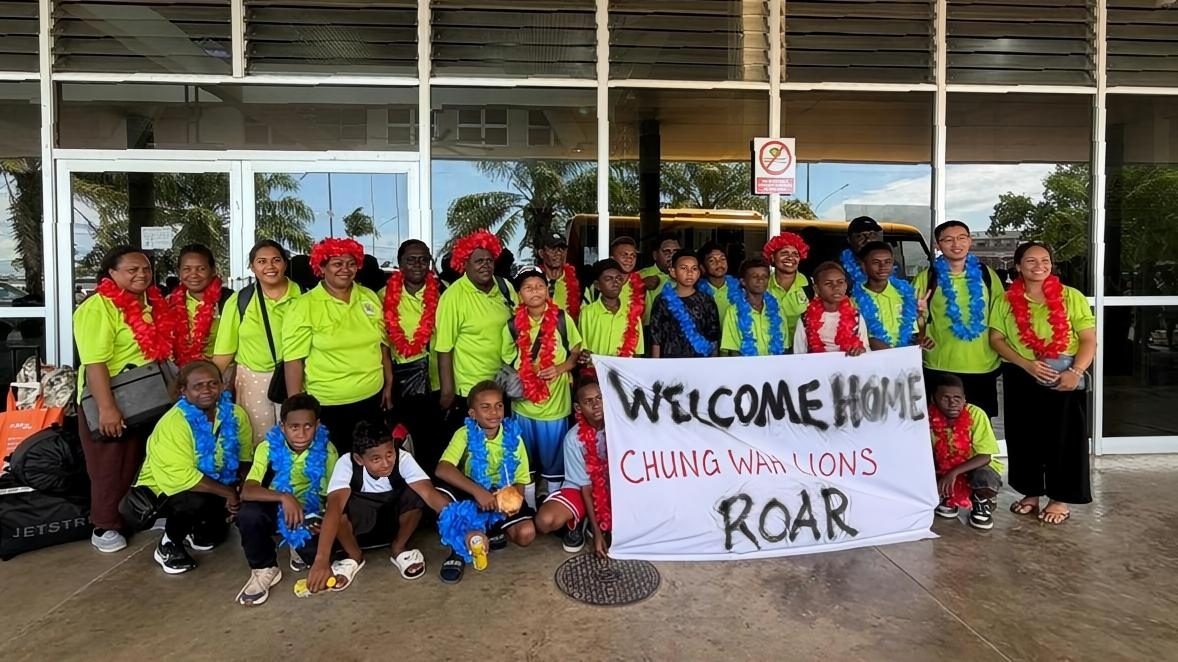 The U12 team home from Australia with a hand-painted welcome banner